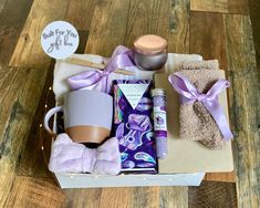 a gift box filled with personal care items on top of a wooden floor next to a cup