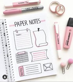 a notebook with pink pens and paper notes on it next to some other items that include scissors