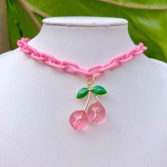 a pink choker with two cherries attached on a mannequin neckline