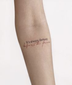 a woman's arm with the words it's always darkest in red ink