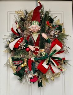 a christmas wreath with an elf doll hanging from it's side on a door