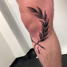 a man with a tattoo on his leg that has a feather and letter s on it