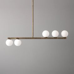 a chandelier with five white balls hanging from it's brass finish frame