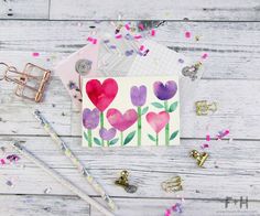 a card with watercolor hearts on it and confetti scattered around the cards