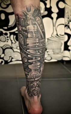 a man's leg with tattoos on it and a motorcycle engine in the background