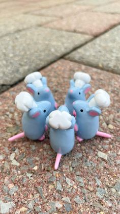 four blue plastic mouses with pink legs and ears on top of each other, sitting on the ground