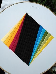 there are many different colors of paper on the table cloth that is being sewn together