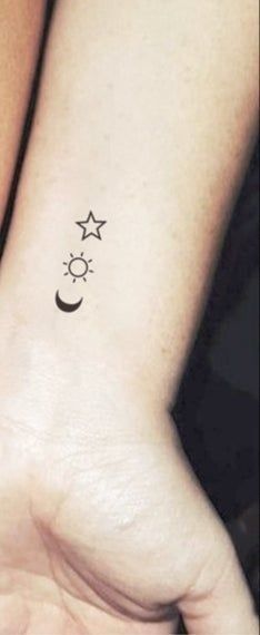 two wrist tattoos with stars and moon on them