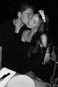 a man kissing a woman on the cheek at a table with plates and utensils