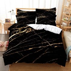 a bed with black and gold marble print on it, next to a white chair