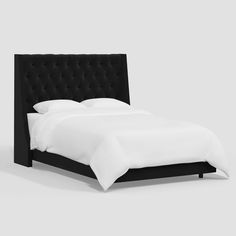 a bed with white sheets and black headboard on it's side, in front of a gray background