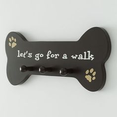 a black dog bone with paw prints on it that says, let's go for a walk