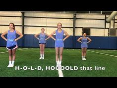 four girls in blue shirts and shorts are standing on the soccer field with their hands on their hips