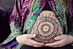 a pregnant woman holding her belly decorated with henna