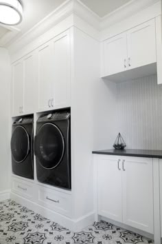 a washer and dryer in a white laundry room with black tile flooring