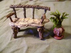 a miniature bench next to a small potted plant on a cloth covered tablecloth