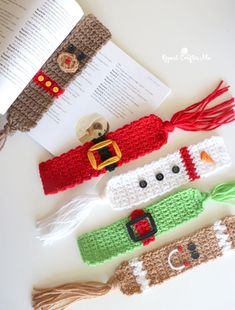 three crocheted bookmarks sitting on top of a table next to an open book