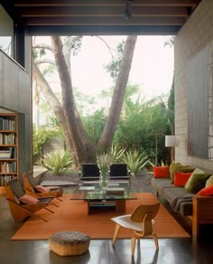 a living room filled with furniture and lots of trees in the back drop down area