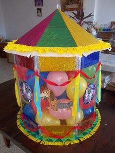 a carnival tent with balloons and streamers on the table in front of it,