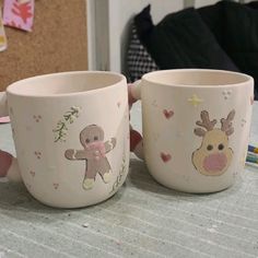 two coffee mugs sitting on top of a table next to each other, one with a teddy bear and the other with a giraffe