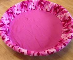 a pink and red dog bed sitting on top of a wooden floor