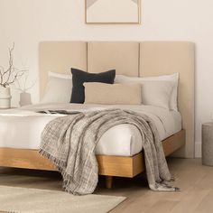 a bed with white sheets and pillows on top of it next to a wooden floor