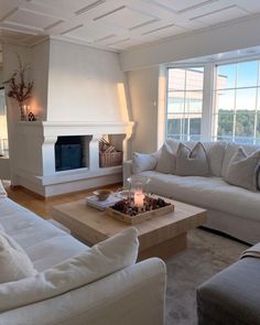 a living room filled with white furniture and a fire place in the middle of it