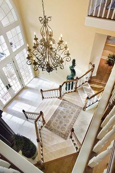 an overhead view of a staircase with chandelier and rugs on the floor