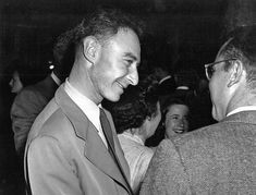 black and white photograph of two men in suits talking to each other at an event