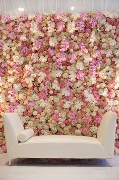 a white couch sitting in front of a flower wall with pink and white flowers on it