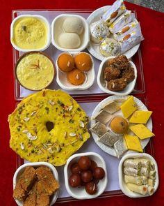 a tray filled with different types of food on top of a red tablecloth covered floor