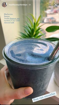 a hand holding a cup filled with blue liquid