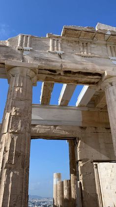 an old building with columns and pillars in front of the cityscape, against a blue sky