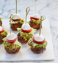 mini burgers topped with lettuce, tomatoes and sour cream on a white plate