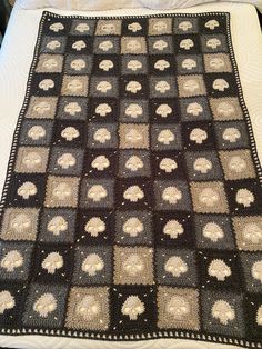 a crocheted blanket on top of a bed with white and black bedspread