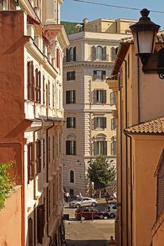 an alley way between two buildings with cars parked on the street and in front of them