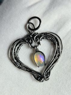 Wanted to make a few Valentine's Day dangle heart pendants like I did a couple of years ago... they are similar in design but not a copy of each other. Totally a free flow design. The bail and the stones/crystals "dangle". This pendant features a lovely ethiopian opal with a rainbow of color flashes ... wrapped in sterling and argentium silver wires. Oxidized and polished... Will come with the stainless steel chain seen in the photos (20 inches long) and also with polishing cloth and gift box Pl Opal Wire Wrapped Necklace As Gift, Gift Opal Necklace With Wire Wrapped Detail, Silver Opal Wire Wrapped Necklace, Heart-shaped Opal Jewelry For Gifts, Spiritual Wire-wrapped Opal Jewelry, Heart Pendants, Flow Design, Wrapped Necklace, Diy Bracelet Designs