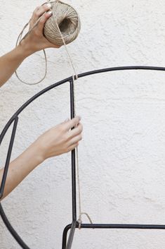 a woman is holding a ball of twine in her hand and pulling it up