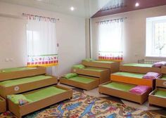 a room filled with lots of bunk beds next to a window and rug on the floor