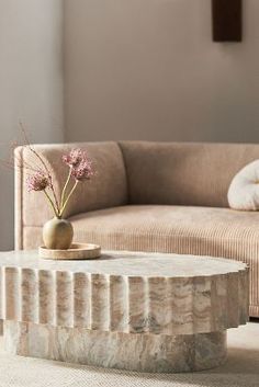 a living room scene with focus on the coffee table and flowers in front of the couch