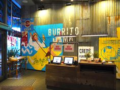 the interior of a restaurant with colorful signs on the wall and wooden tables in front of it