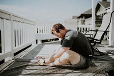 a man is sitting on the deck looking at his cell phone while he sits down