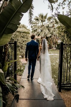 a bride and groom walking down a walkway