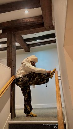 a man in white jacket and camo pants standing on stairs with his feet up