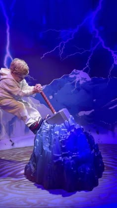 a man with a hammer on top of a rock in front of a blue background