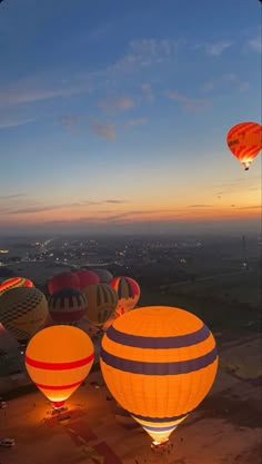 several hot air balloons are lit up in the sky at dusk, with lights on them