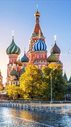 the cathedrals are painted in different colors and sizes, with trees around them on either side of the water