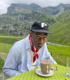 a man sitting at a table with a cup of coffee in front of his face