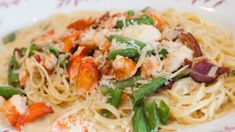 pasta with shrimp, asparagus and scallops on a white plate topped with parmesan cheese