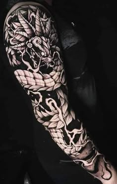 a man's arm with a dragon and snake tattoo design on it, in black and white